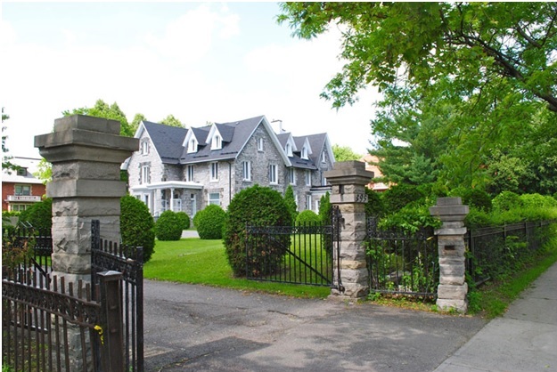 Exterior view of a two and a half storey Gothic Revival style limestone home with white trim built in 1871